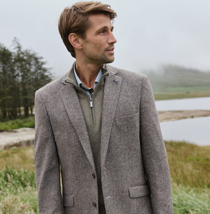 Man wearing grey, tweed blazer jacket and dark, blue jeans